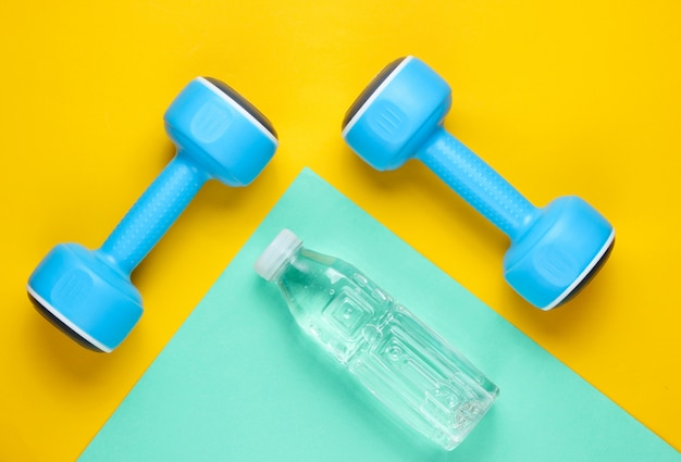 Blue dumbbells and a bottle of water