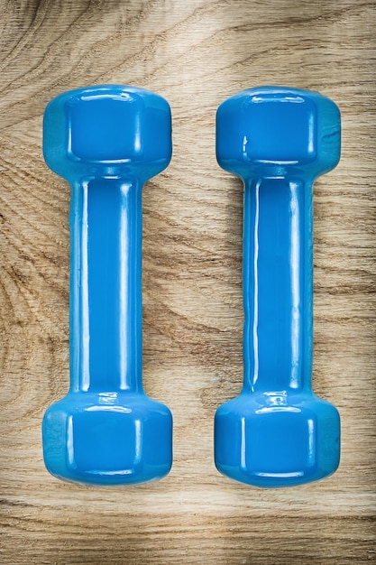 Photo blue dumbbells on wooden board fitness concept.