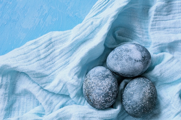 Blue Easter eggs on blue background. Naturally Eggs painted with hibiscus with marble stone effect. Eco paint.