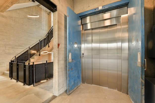 A blue elevator door in a building with a staircase