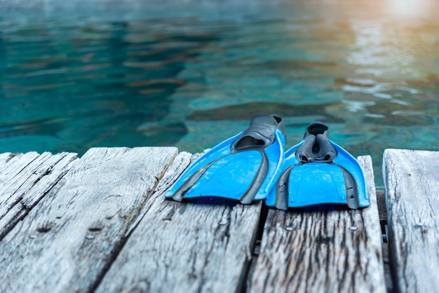 Blue fin or flipper put on the wooden floor in front of the pool.