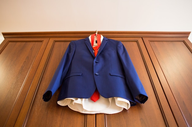 Photo blue groom suit with red tie hanging wooden cabinet