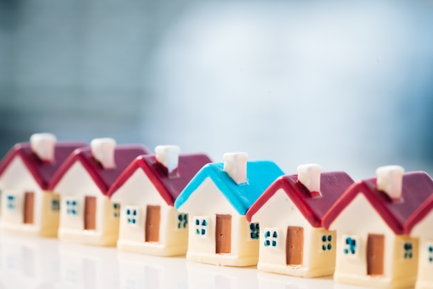 Blue house model among red house with city backgrounds.