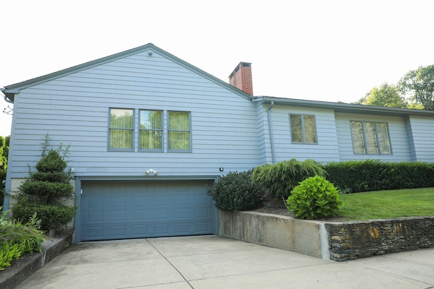 A blue house with a blue garage door and a green bush