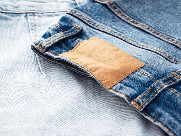 Blue jeans with a brown leather blank label closeup Jeans texture Fashion denim background for sewing copy space Label on clothing for indicate the size company