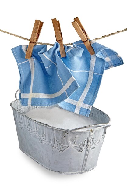 A blue kitchen napkin hangs on clothespins over an iron bowl of foam The concept of hand washing clothes