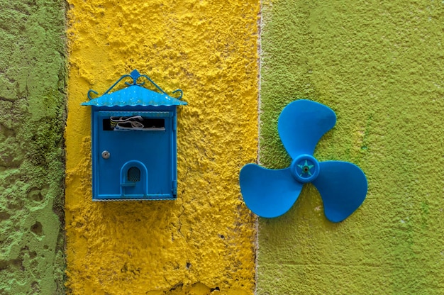 Blue mailbox and small propeller on colored wall