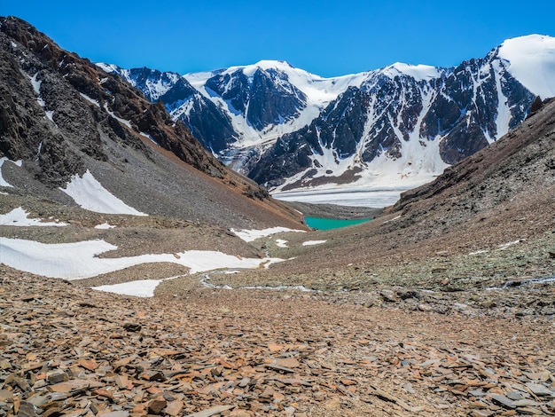 Blue mountain lake in the caldera. Mountain range against a blue cloudy sky. Caldera of an extinct volcano is surrounded by a mountain range. In the valley there is a blue lake with steep rocky shores