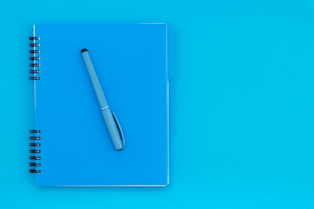 Blue notebook with a pencil on a blue background. Flat Lay Template. Place for text