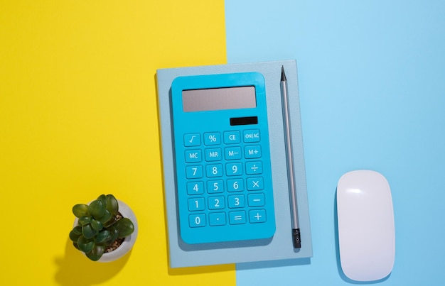 Blue notepad calculator and wooden pencil on a blue background