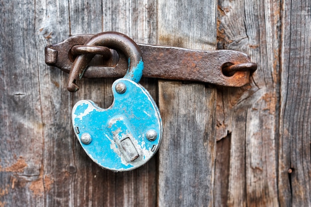 Blue old rusty unlocked padlock on wooden door