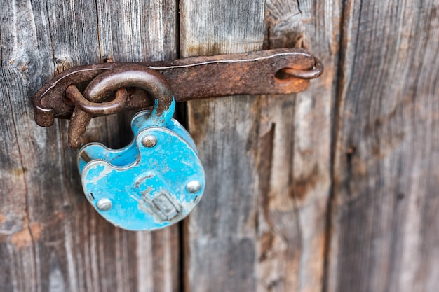 Photo blue old rusty unlocked padlock on wooden door