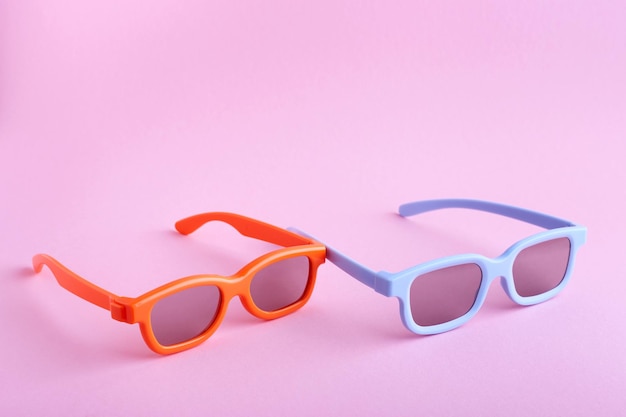 Blue and orange 3D glasses on a pink background Fronttop view