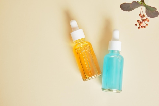 Blue and orange serums in transparent dropper bottles on a beige background natural cosmetics and skin care