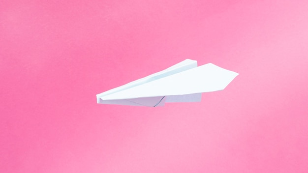 Blue origami plane on pink background, travel flights copy space.