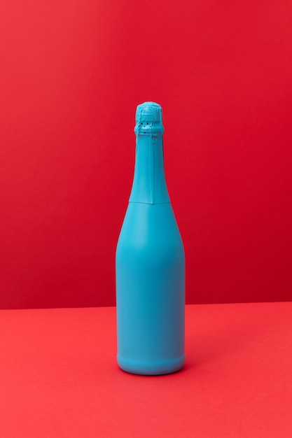 Blue painted spray wine bottle on a duotone red background