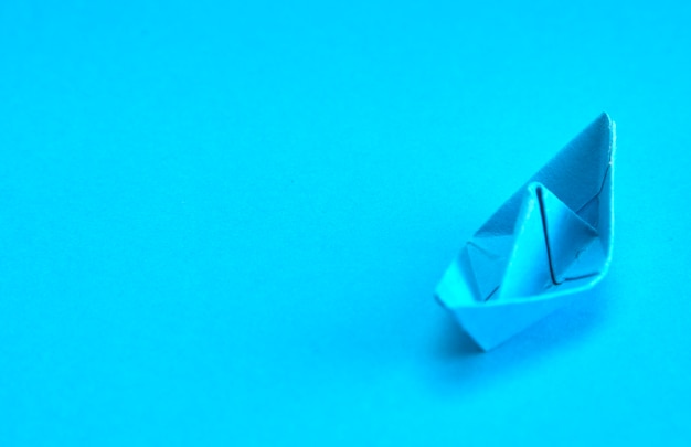 Blue Paper boat on cyan background.  Concept for leadership,