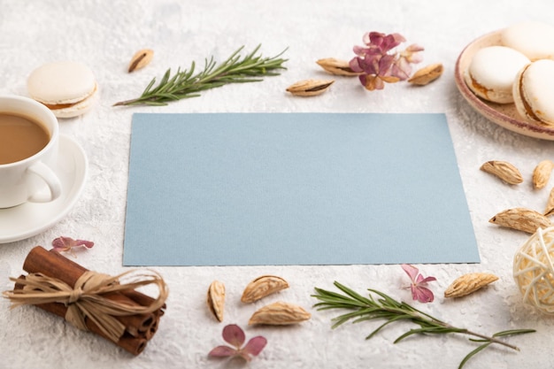 Blue paper sheet mockup with cup of coffee almonds and macaroons on gray concrete background business card side view