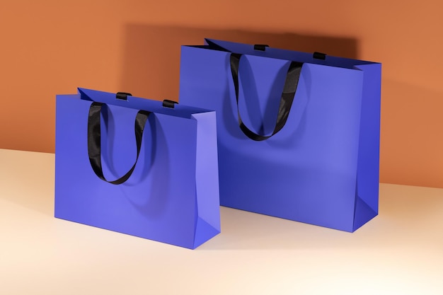 Blue paper shopping bags mockup with black handles on colorful background