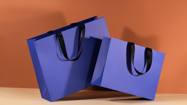 Blue paper shopping bags mockup with black handles on colorful background