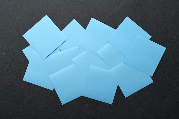 Blue paper stickers on black background Sticky notes blank with copy space ready for your message New year goals or resolutions concept Blue Monday idea Flat lay copy space on black background