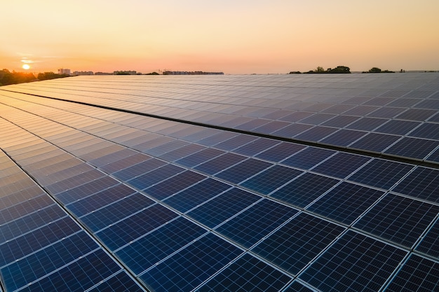 Blue photovoltaic solar panels mounted on building roof for producing clean ecological electricity at sunset. Production of renewable energy concept.