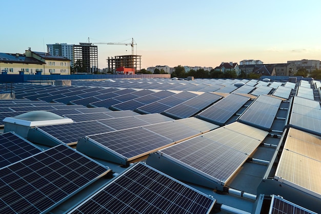 Blue photovoltaic solar panels mounted on building roof for producing clean ecological electricity at sunset. Production of renewable energy concept.