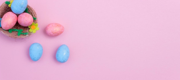 Blue and pink Easter eggs in a nest on a pink background Flatly Copy space Banner