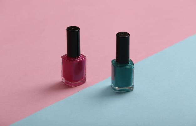 Blue and pink nail polish bottles on a pastel background Beauty still life