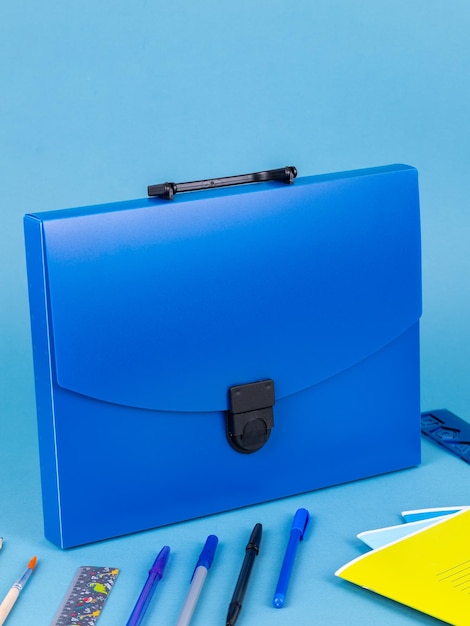 Photo blue plastic briefcase folder for documents and school items on a bright blue table