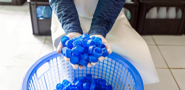 Blue plastic water bottle cap in hand worker in drink water factory