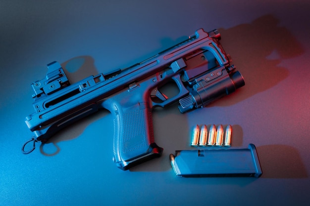 A blue and red gun is on a table with a blue background.