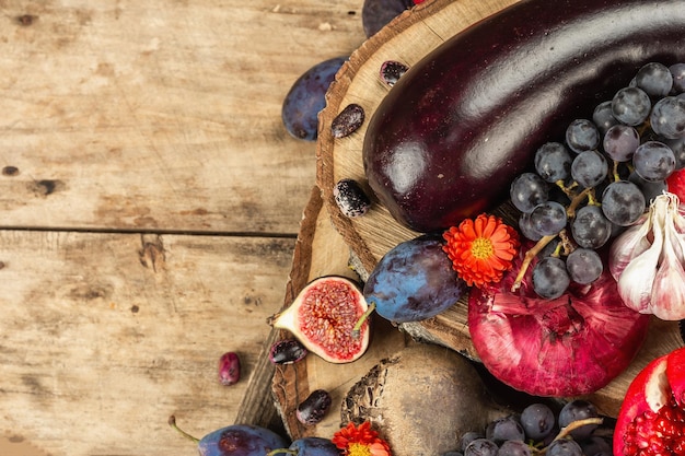 Blue, red and purple food. Culinary background of fruits and vegetables. Fresh figs, plums, onion, eggplant, grape, cabbage, apple, garlic, dogwood, pomegranate, beetroot. Wooden stands and old boards