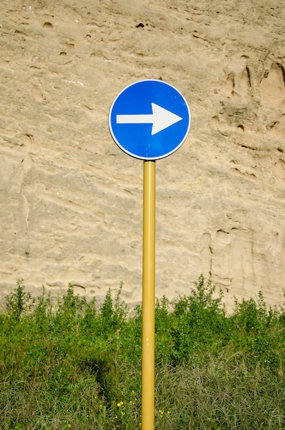 Photo blue road sign with arrow on weathered ancient wall