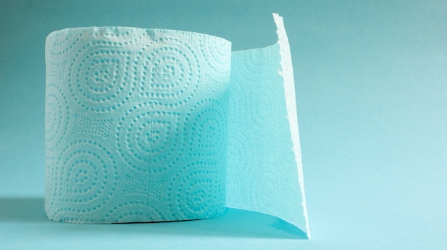 Blue roll of modern toilet paper on a blue background. A paper product on a cardboard sleeve, used for sanitary purposes from cellulose with cutouts for easy tearing. Embossed drawing. copy space.