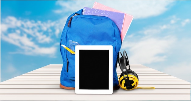 Blue School Backpack  with tablet and earphones on   background.