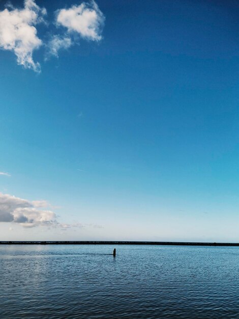 Blue sea ocean water surface background Concept of travel and summer holiday vacation in calm scenic place Copy space and nature Horizon and sky with clouds People walking in the middle