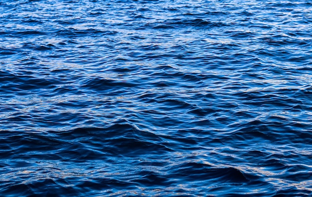 Blue sea waves in sunshine glow as surface background summer holidays and coastal nature concept