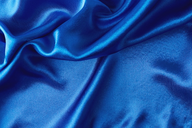 Blue silk background with folds.  Abstract texture of rippled satin surface