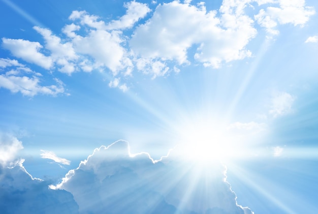 Blue sky background with clouds and sun rays coming out