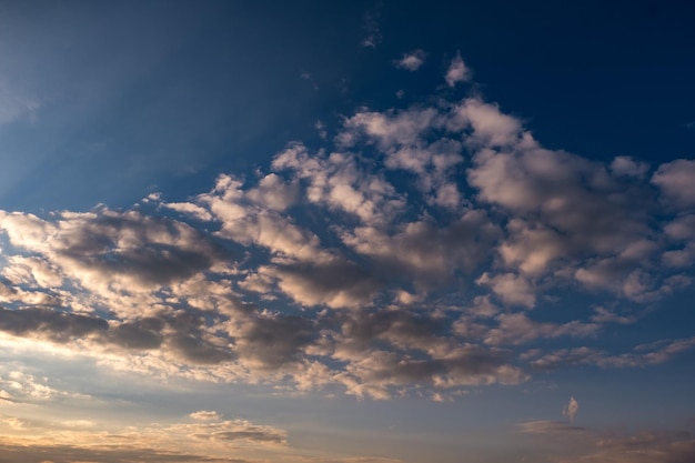 Blue sky background with evening fluffy curly rolling clouds Good windy weather