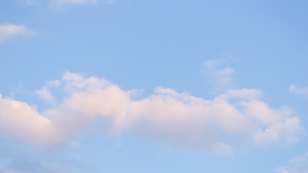 Blue sky background with pale pink clouds at sunset