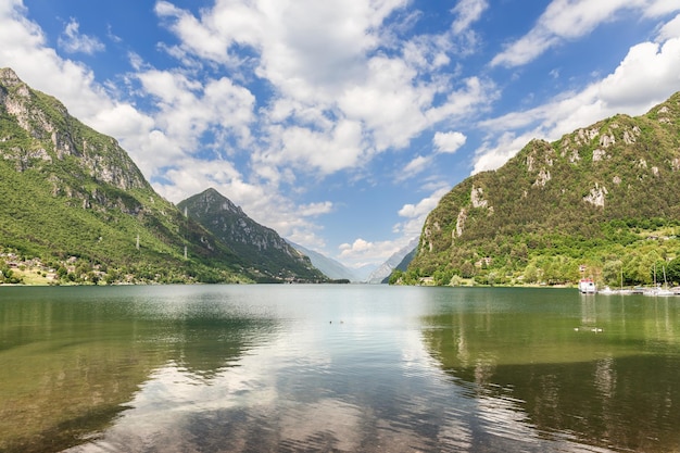 Blue sky reflected in highmountain alpine Lago d'Idro framed by steep cliffs, Lombardy, Italy