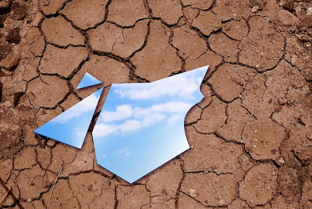 Blue sky reflected in the mirror breaking up on cracked soils Climate change concept