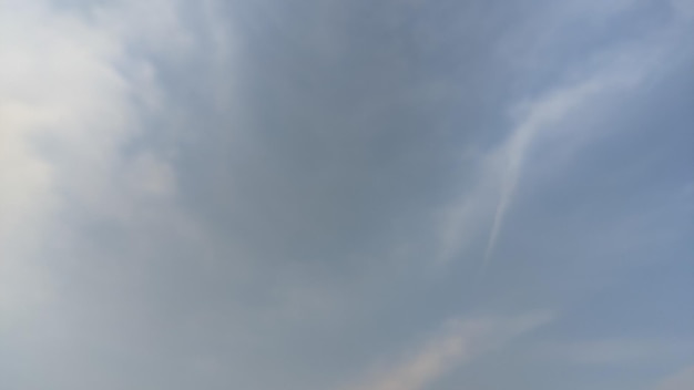 A blue sky with clouds and a white trail in the middle.