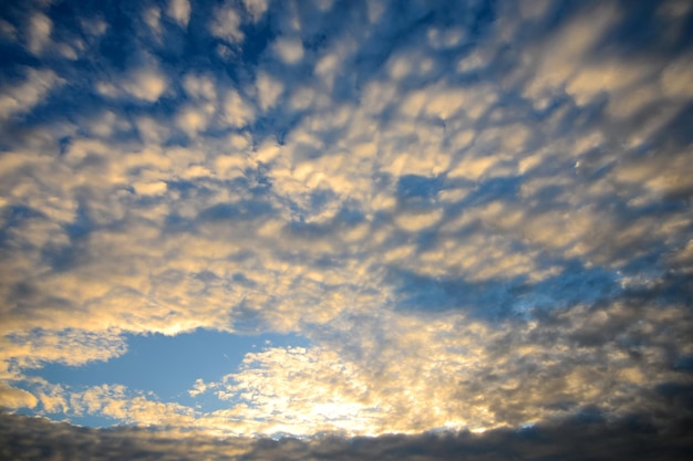 The blue sky with golden fluffy clouds and sun