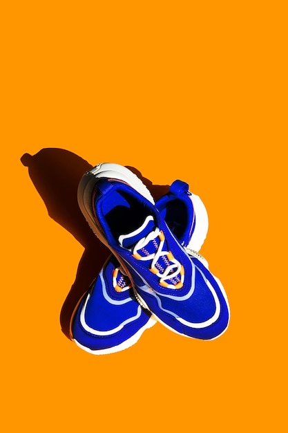 Blue sneakers on orange background Trendy sport shoe street casual footwear