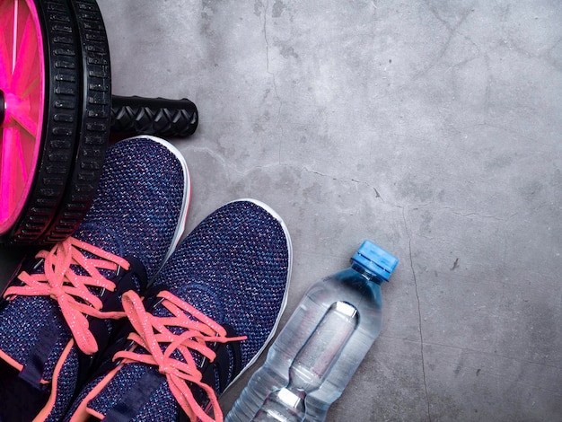 Blue sneakers with coral color shoelacer bottle of water sport wheel on stone background Concept of healthy lifestile everyday training and force of will