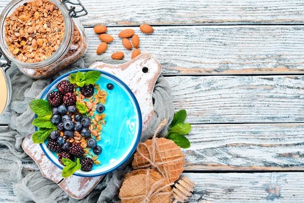 Blue Spirulina and Fresh Fruit Smoothie Bowl Topped with blackberries, blueberries, granola and yogurt. Breakfast. Top view. Free space for your text.