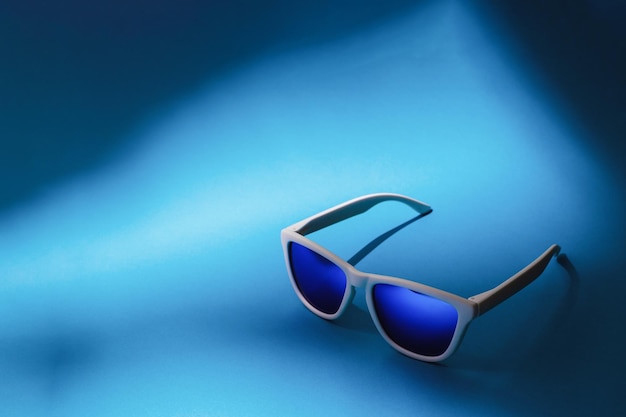 Blue sunglasses on blue background with copy space. Studio shot of sunglasses on colorful background